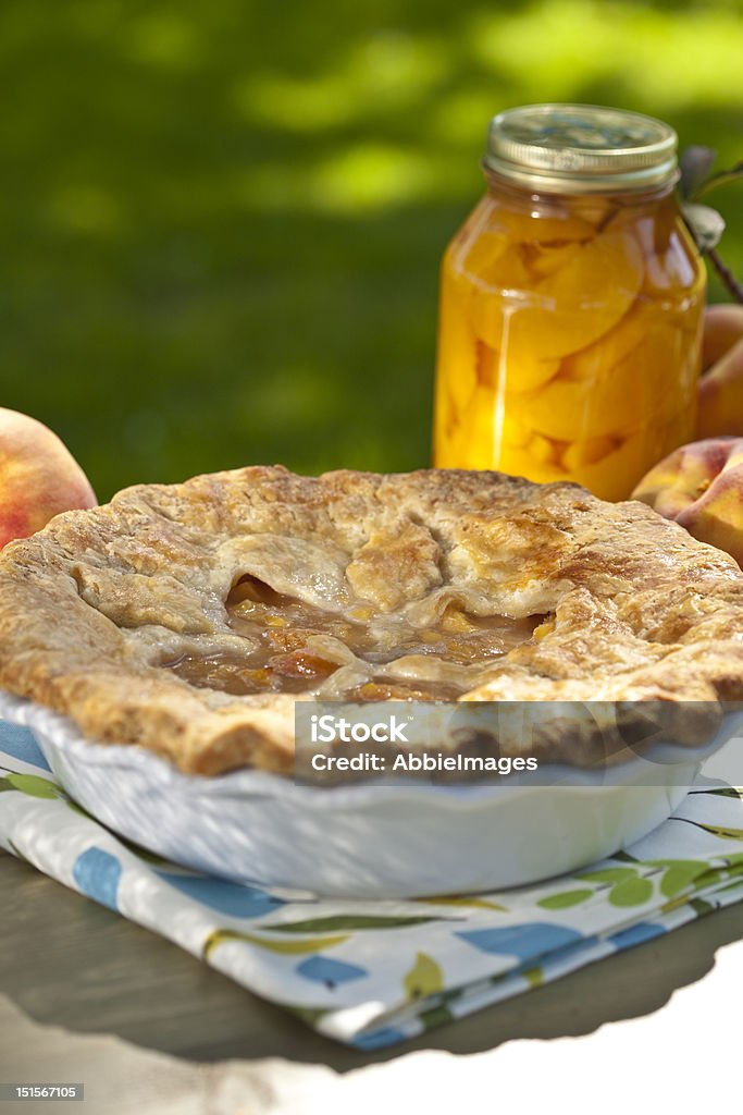 Peach Pie Homemade peach pie outdoors with a jar of peaches in the background. Baked Stock Photo