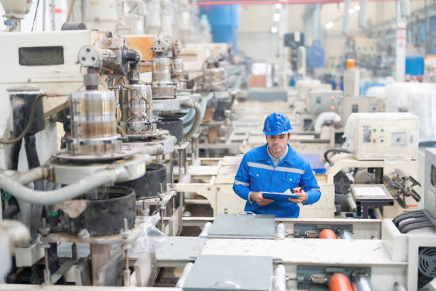 istock American male engineer He looked down at the working machinery. to check the electronic system holding a list note and a radio Wear a helmet and uniform. in large plastic and steel factories 1515687346