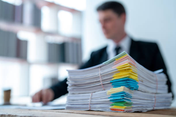 Selective focus of stack of paperwork on office desk isolated over with businessman working