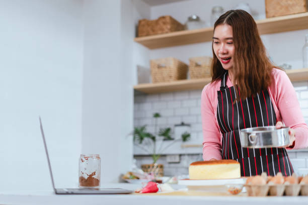 istock Live Culinary, Woman Making and Decorating a Cake in the Kitchen, Streamed Online from her Laptop 1515696833