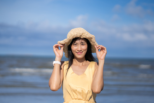 Asian young woman enjoy sea on vacation coconut tree coasting line at sea side.