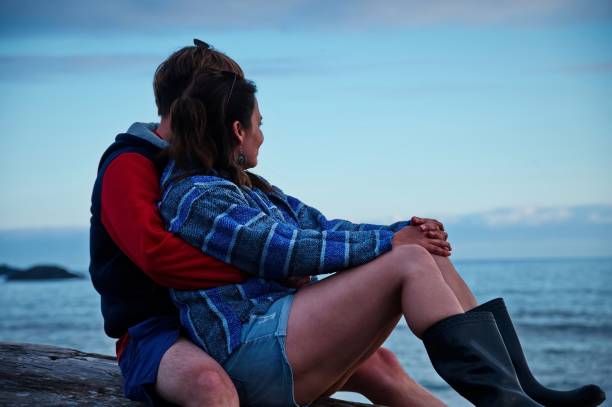 istock Couple sitting on a tree trunk on the beach 1515726738