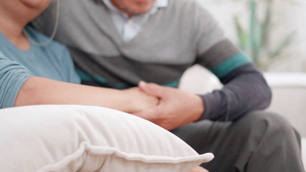 The elderly couples talking about health together and encouraging each other in a cozy home. Senior wife and husband sitting on the couch in the living room embrace and take care of each other. Concept of family, life insurance, healthcare. las parejas de ancianos hablan de salud juntos y se animan mutuamente en un hogar acogedor. la esposa mayor y el esposo sentados en el sofá de la sala de estar se abrazan y se cuidan el uno al otro. concepto de familia, seguro de vida, salud.