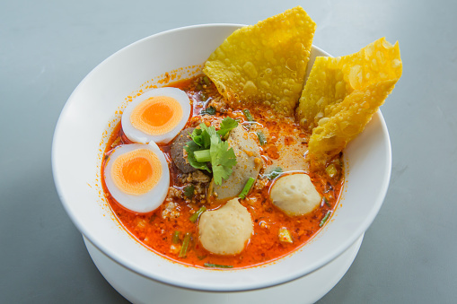 Spicy tom yam noodle soup with pork boiled egg and crispy dumplings - Asian style