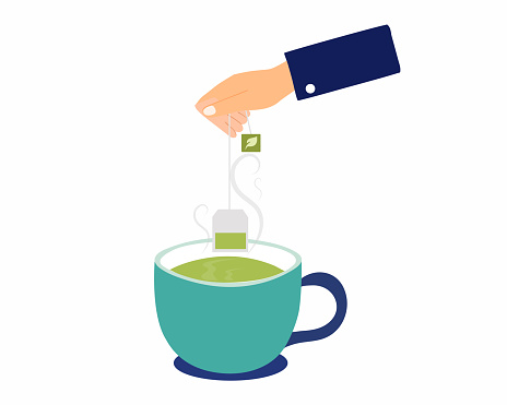 Men hand holding tea bag and dipping green tea into a cup Good start in the morning before beginning the working day.