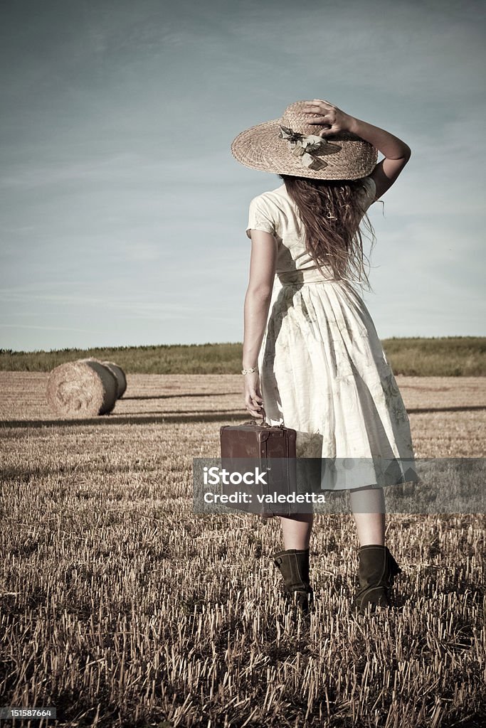 Beautiful 20's retro woman walking in the field Beautiful 20's retro woman walking in the field and holding an old suitcase Retro Style Stock Photo