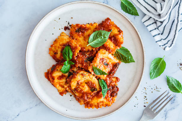 istock Ravioli with ricotta, tomato sauce and basil, white marble background. 1515877654