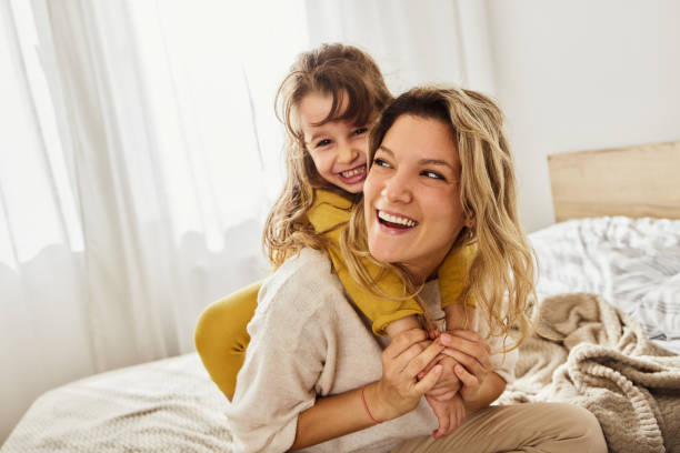 istock Cheerful single mother and daughter having fun on a bed. 1515885342