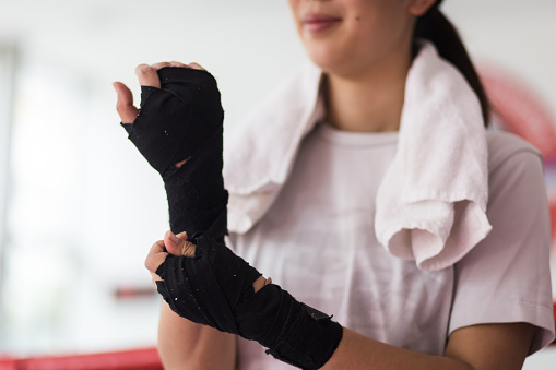 Young Asian woman wrapping a protective bandage before boxing training in a gym