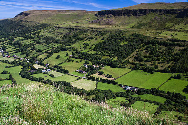 Irish Glen Deep Irish glen in County Antrim looking from the mountain-top down on the patchwork of green fields and farms. glenariff photos stock pictures, royalty-free photos & images