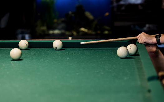 Billiard balls on a table close up. hand with the cue is preparing to strike