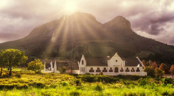 Cape Dutch architecture in the wine regions of the Western Cape African boer house against misty mountains in sunset light. Shot at wine farm/estate, near Stellenbosch, Western Cape, South Africa. stellenbosch stock pictures, royalty-free photos & images