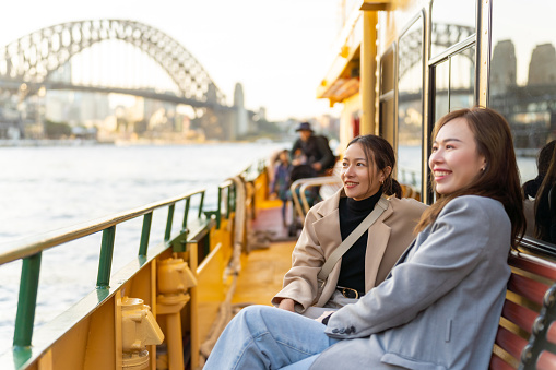Asian woman friends travel on ferry boat crossing Sydney harbour in Australia.