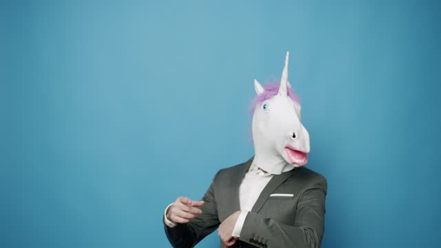 Cool guy in suit and unicorn mask dancing.