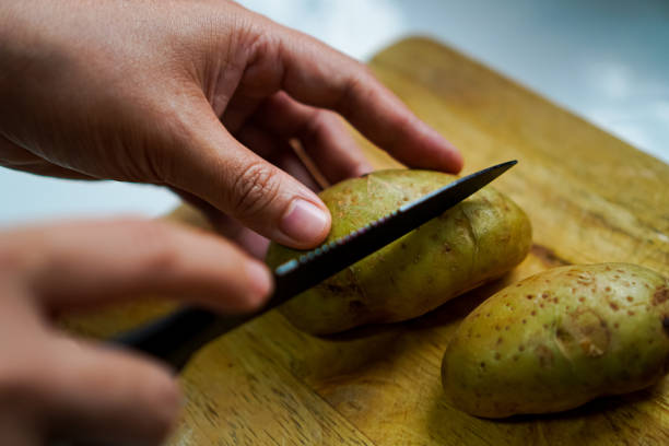 istock Image showing potato slices placed on a wooden chopping board to prepare a vegetarian mashed potato spread. 1516075892