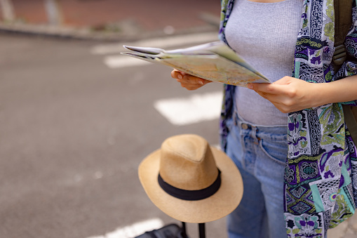 Close up of unrecognizable tourist going through city map on the street. Copy space.