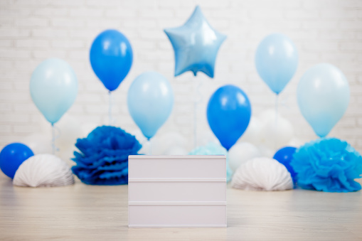 birthday congratulation concept - colorful air balloons, paper balls and blank lightbox with copy space over white brick wall background