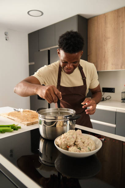 istock Young african man preparing boiled chicken mince with vegetables recipe. 1516107526