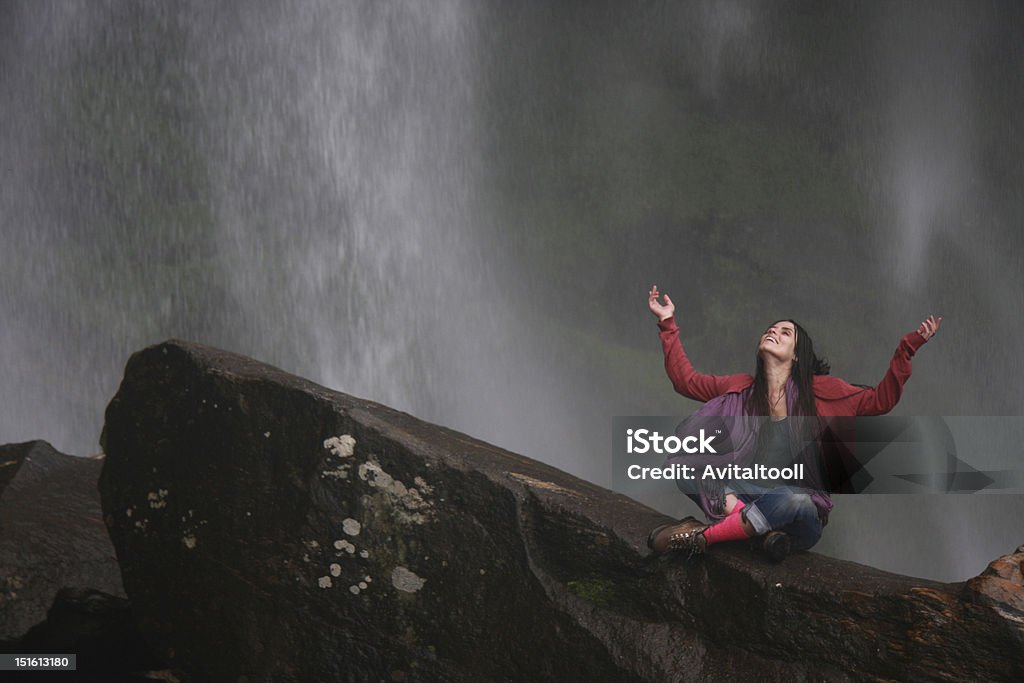 Happiness Waterfall Happy girl sitting by a waterfall. Adult Stock Photo