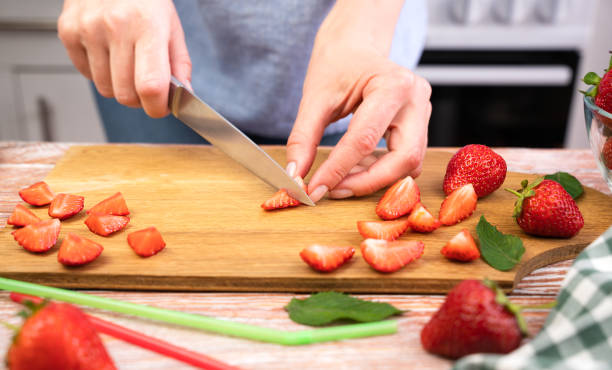 istock Women's hands cutting strawberry for lemonade on the table in the kitchen. Close-up. Selective focus. 1516140489