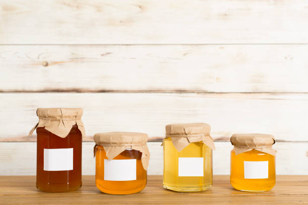 frascos com mel sobre mesa de madeira. design de maquete - honey purity raw pollination - fotografias e filmes do acervo