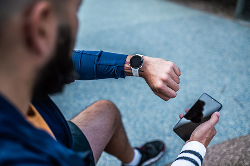 Using smart watch at a fitness tracker and phone to check workout data