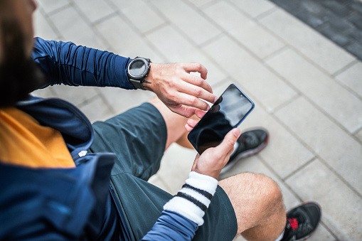 Using smart watch at a fitness tracker and phone to check workout data