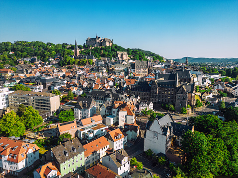 Aerial view of Marburg, Germany with stunning architecture, surrounded by lush greenery and a river valley.