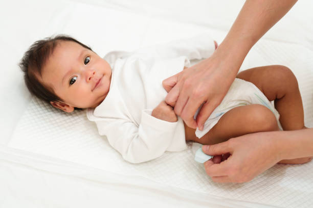 istock mother changing diaper of newborn baby while lying on bed 1516215862
