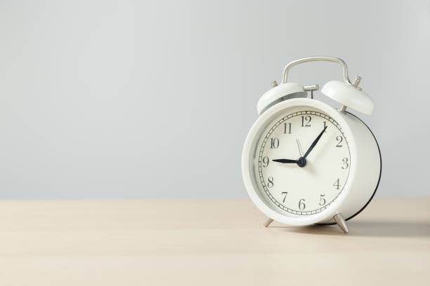 istock white retro alarm clock on wooden table. 1516265167