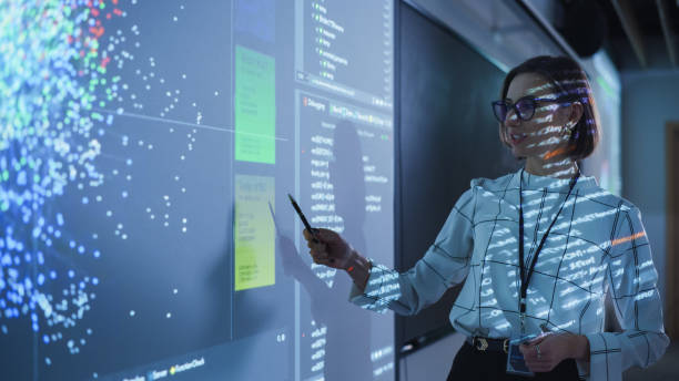 istock Young Female Teacher Giving a Data Science Presentation in a Dark Auditorium with Projecting Slideshow with Artificial Intelligence Neural Network Architecture. Business Startup and Education Concept 1516276543