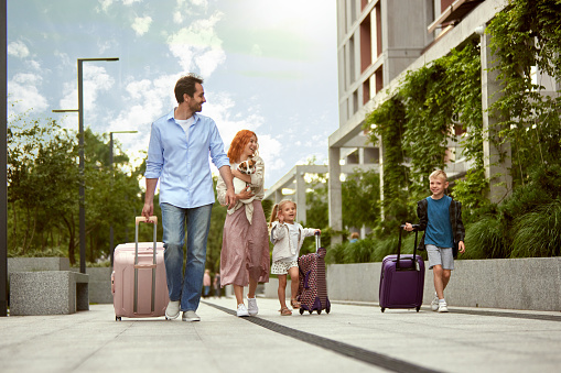 Young happy family, man and woman, parents going on vacation with little boy, girl and dog. Family trip. Warm summer day. Concept of family, childhood and parenthood, travelling, vacation, ad