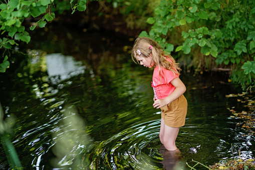 A Happy Girl Embraces the Joys of Childhood as She Explores a Summer Creek, Immersing Herself in Nature's Wonders and Playful Discoveries. Preschool Child and Summertime