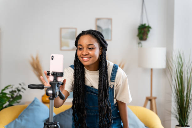 Woman preparing mobile phone on tripod.