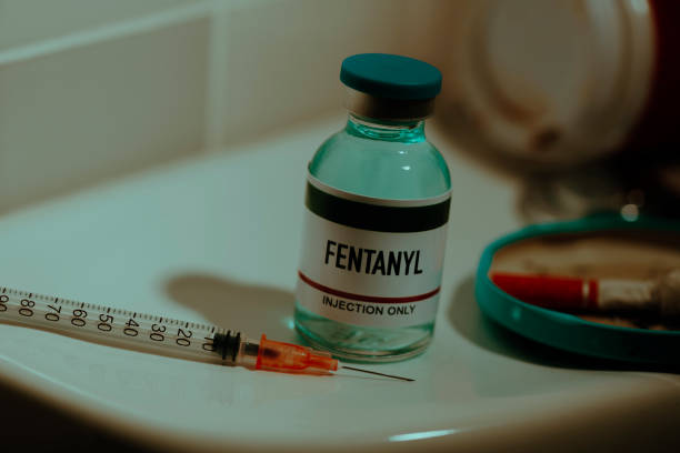 vial of fentanyl and syringe on a toilet a simulated vial of fentanyl and a syringe on the cistern of a toilet in a restroom next to a cigarette butt fentanyl addiction stock pictures, royalty-free photos & images
