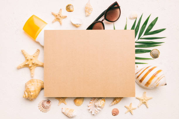istock Summer time concept with blank greeting card and blank craft paper on colored background. Seashells from ocean shore in the shape of frame separated with space for text top view 1516340873