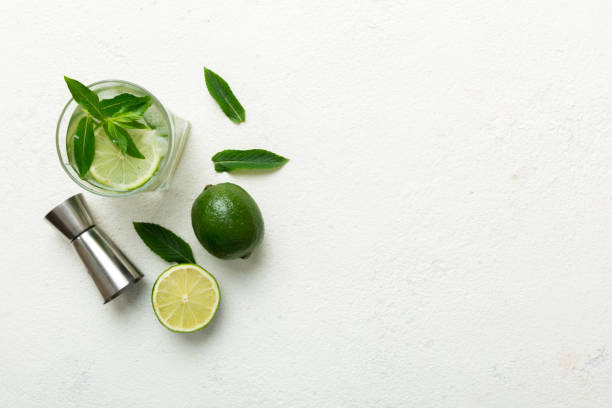 caipirinha, mojito cocktail, vodka or soda drink with lime, mint and straw on table background. refreshing beverage with mint and lime in glass top view flat lay - drink on top of ice food imagens e fotografias de stock