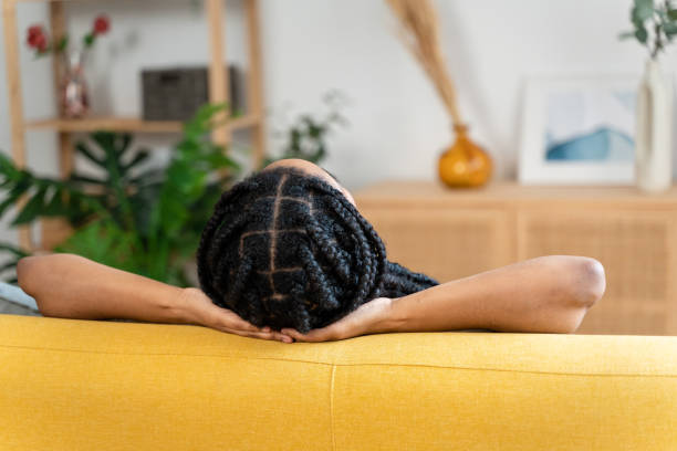Woman with braided hair taking a nap at home.