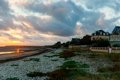 Sunrise view of coastal street of Grandcamp Maisy, a scenic French coastal town in Normandy, with fishing port, sandy beaches, and maritime traditions
