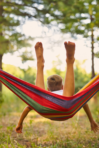 Cute little boy having fun with multicolored hammock in backyard. Summer active leisure for kids. Child on hammock. Activities and fun for children outdoors. Selective focus