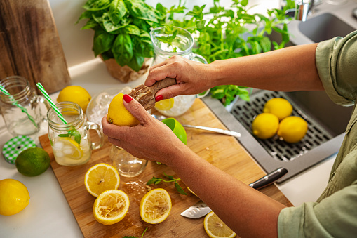 Close up of woman's hands squeezing lemons for lemonade preparation