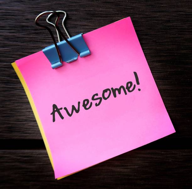 istock Pink note on dark background with handwritten text AWESOME! praise to someone to tell them they are doing good or great job or well done or do something excellent 1516407807