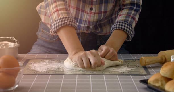 istock Artisan bread working with dough. Handmade bread kneading in kitchen with bakery equipment tools at foreground and black background. Bread-making process for professional baker at work concept. 1516424635