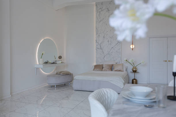 istock minimalistic light elegant luxury design of a modern spacious studio apartment with kitchen area, bedroom and huge mirror behind the couch. tiles on the floor and high ceiling. 1516431636