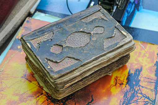 An old worn book with a black cover. On a white background, isolated image