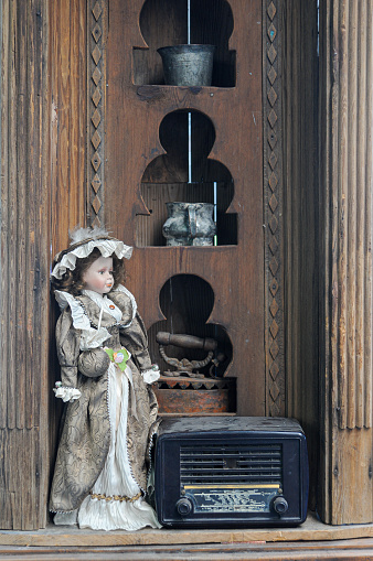 Traditionally dressed doll girl and a radio in front of a closet