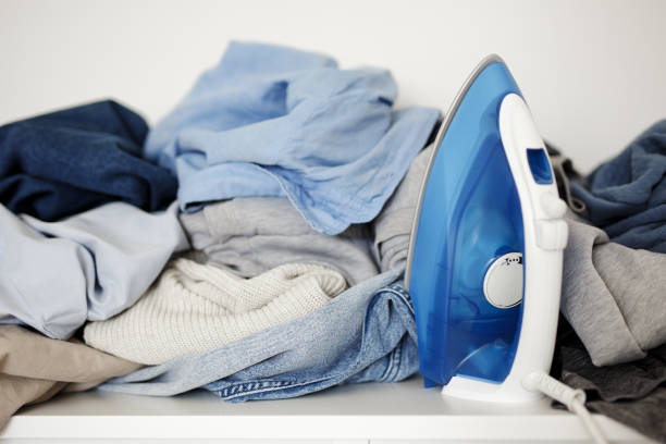 housework concept - close up of wrinkled laundry and iron