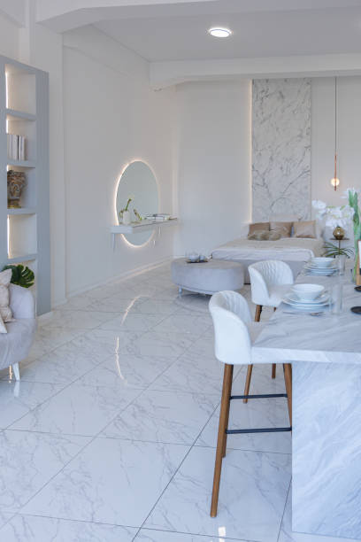 istock minimalistic light elegant luxury design of a modern spacious studio apartment with kitchen area, bedroom and huge mirror behind the couch. tiles on the floor and high ceiling. 1516506264