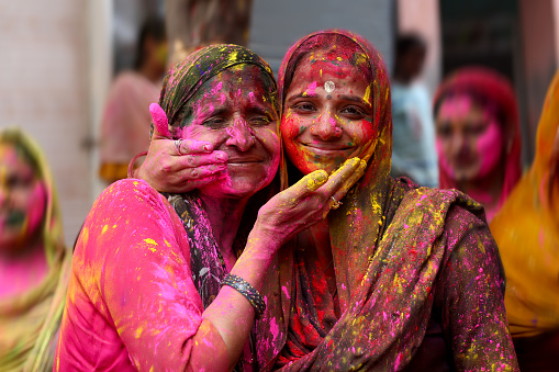 Mature women of Indian ethnicity playing Holi with colors. Holi is a popular and significant Hindu festival celebrated as the Festival of Colours, Love and Spring. It celebrates the eternal and divine love of the god Radha and Krishna.
