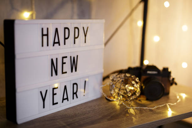 Lightbox z tekstem Szczęśliwego Nowego Roku na stole z zabytkowym aparatem i lampami LED – zdjęcie